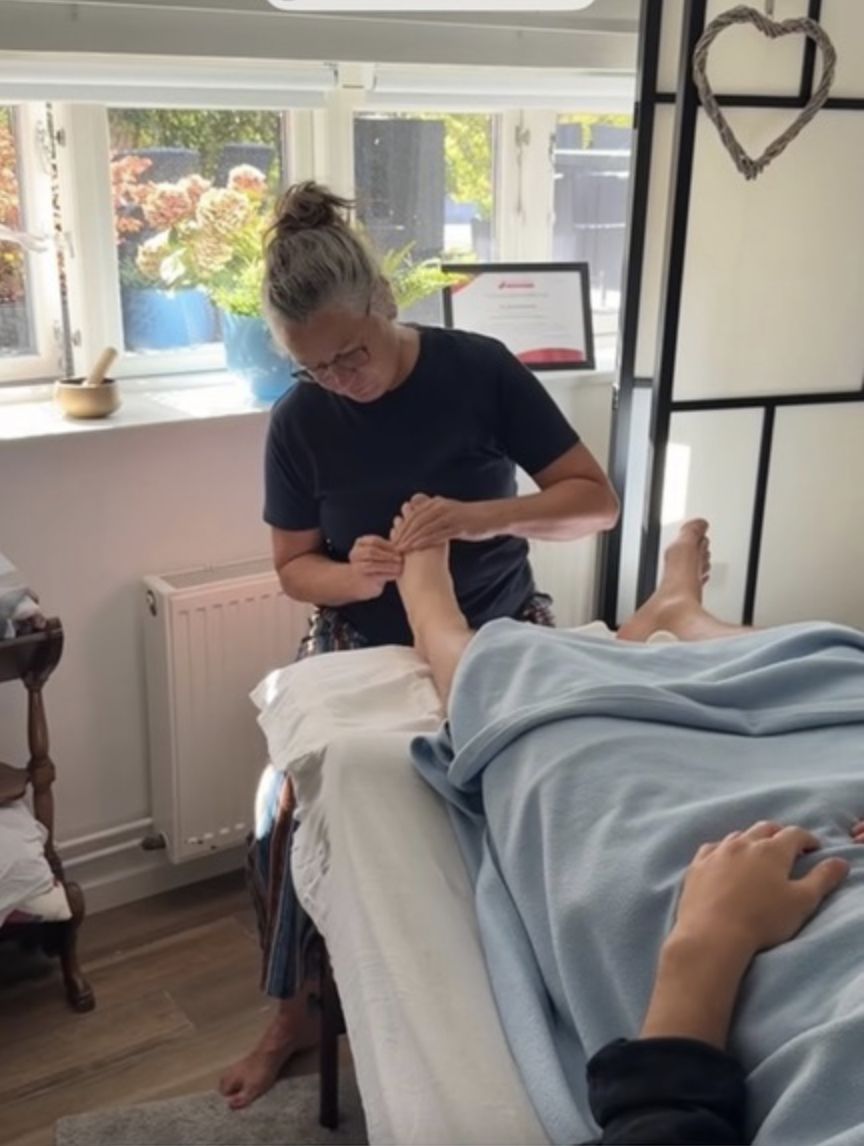 Pia giver zoneterapi på en klients fod i den lyse klinik